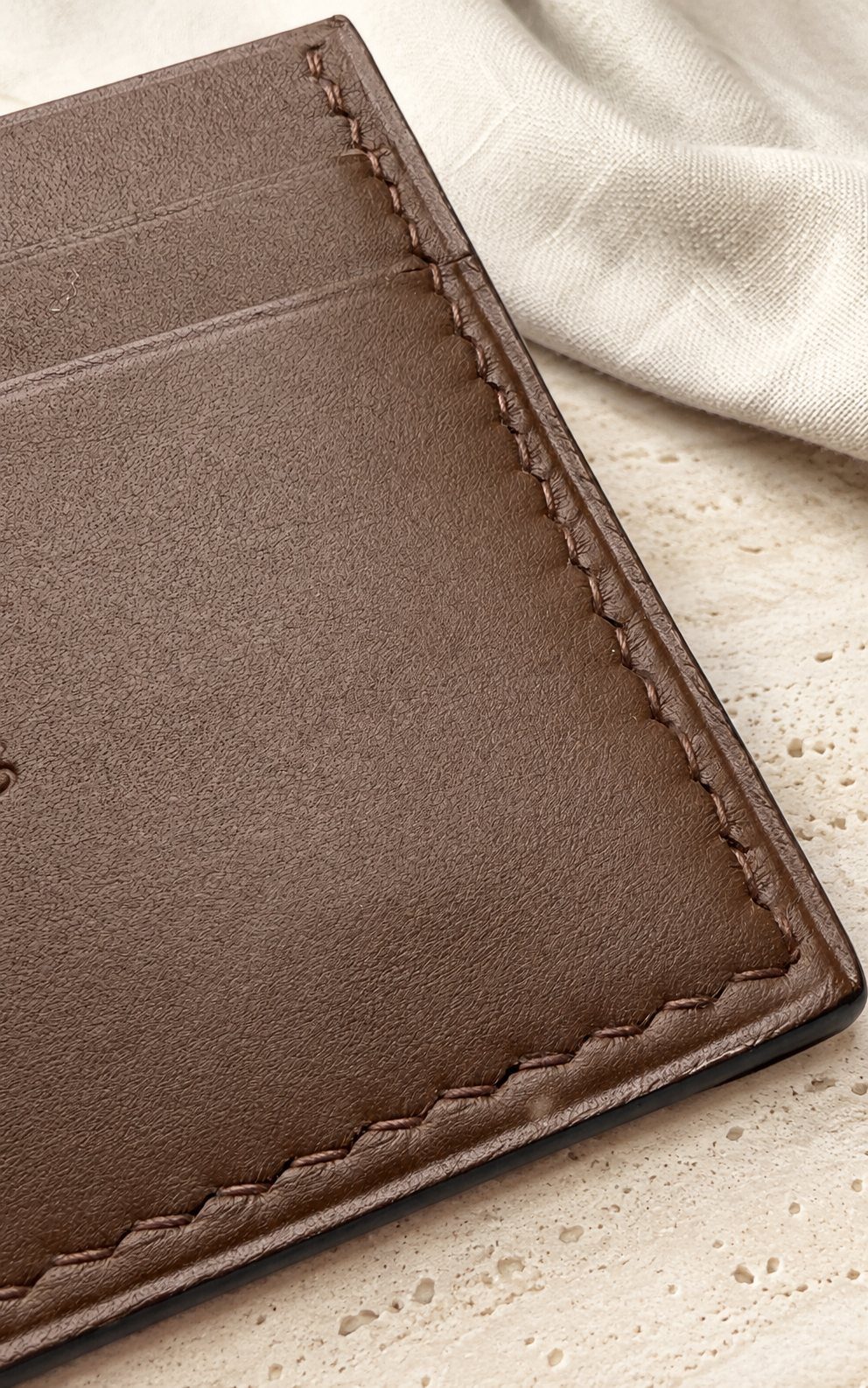 Détail de la texture et des coutures du collection l'île — porte-cartes en cuir cognac