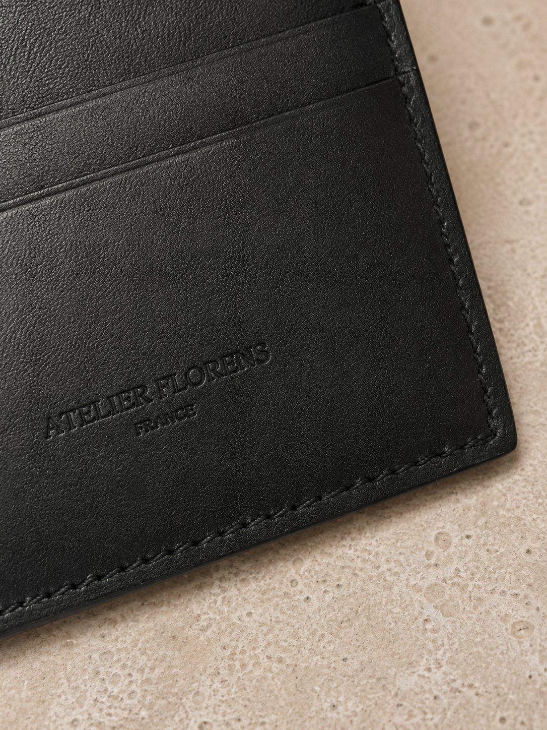 Détail de la texture et des coutures du collection l'île — porte-cartes en cuir noir