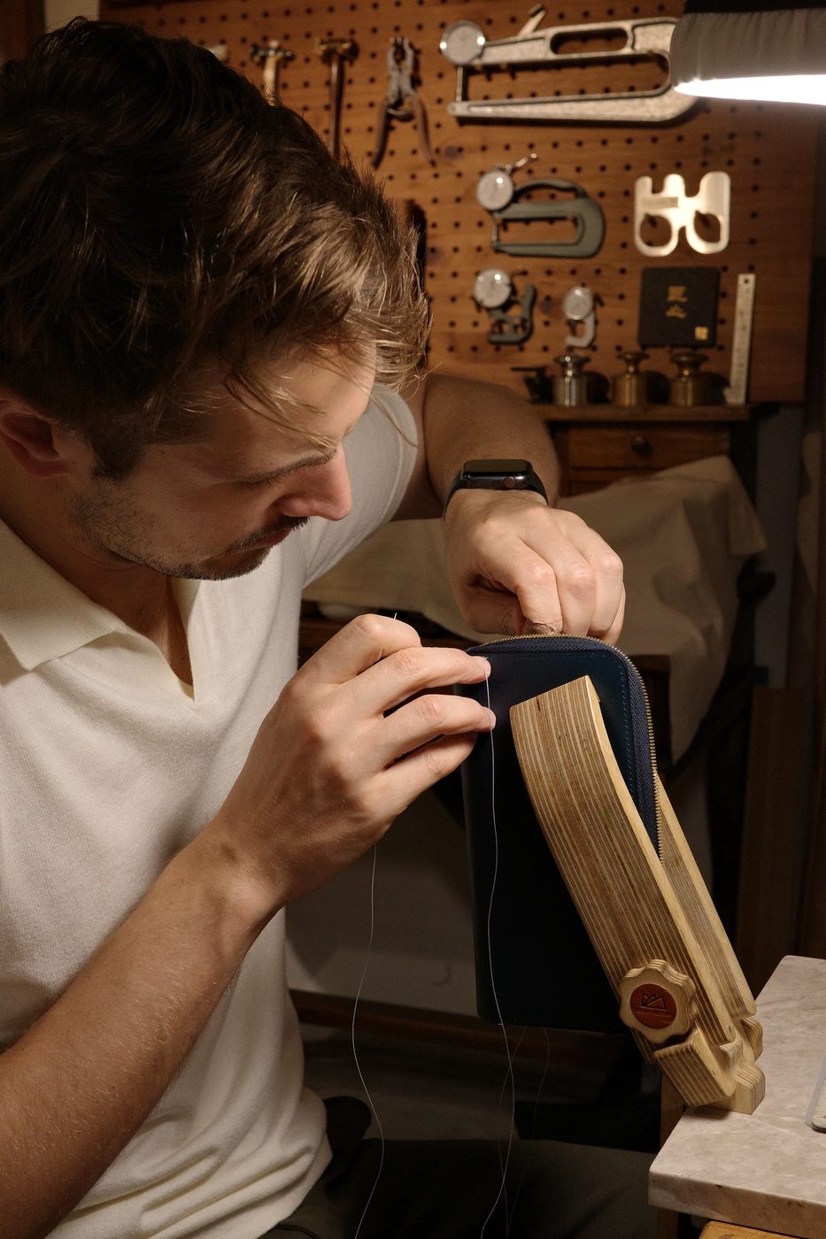 Florian, artisan maroquinier, façonnant une pièce en cuir dans son atelier à Genève