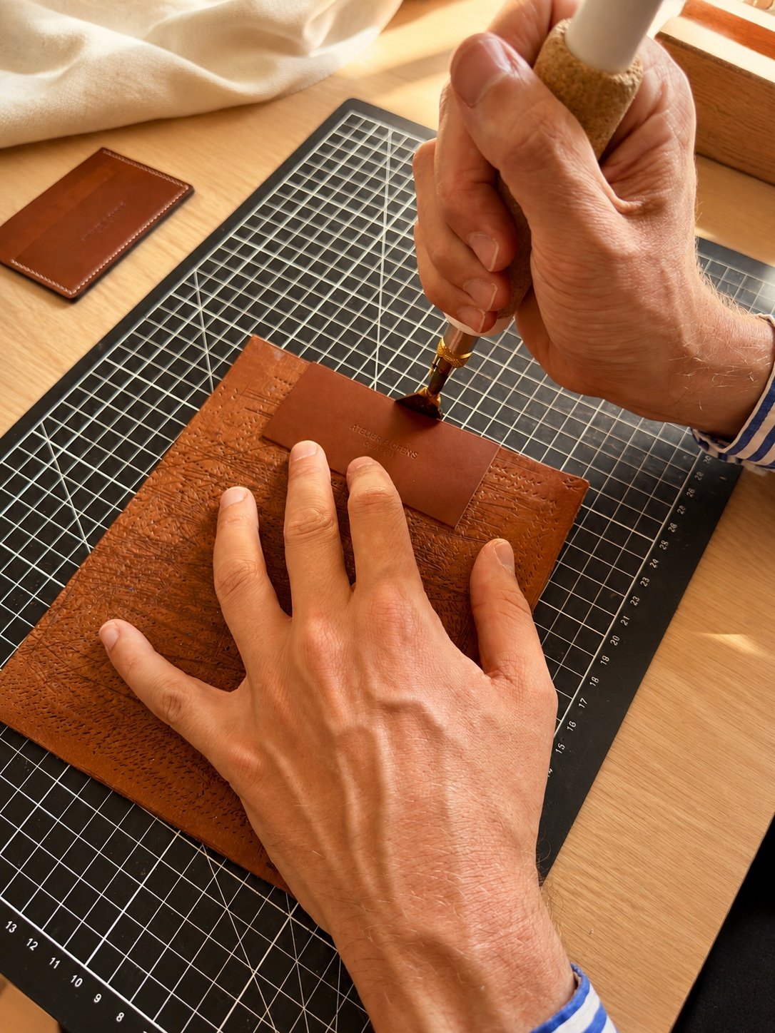 Marquage à chaud du logo Atelier Florens sur une pièce en cuir, dans l'atelier à Genève